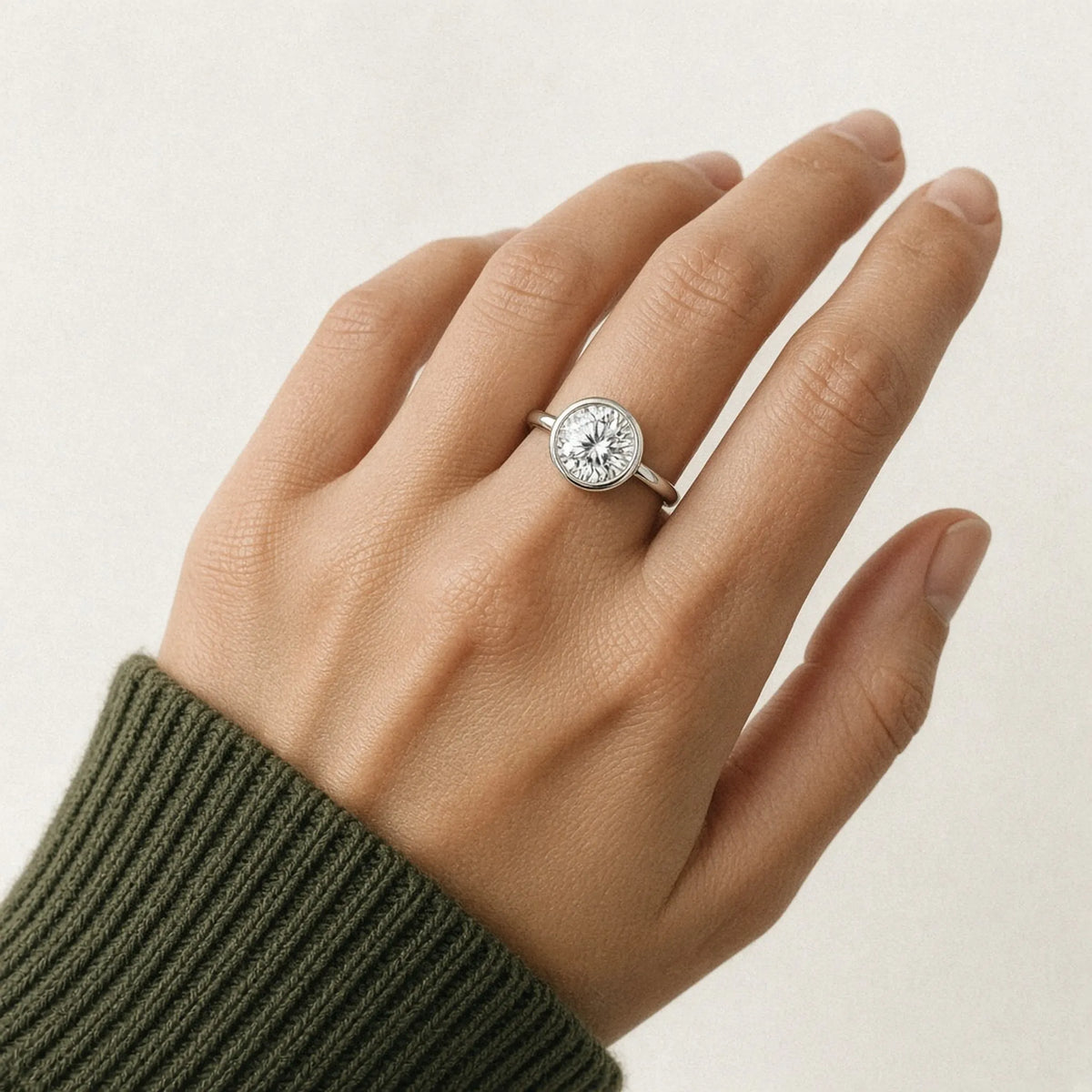 Bezel-set round lab-grown diamond ring on the left ring finger