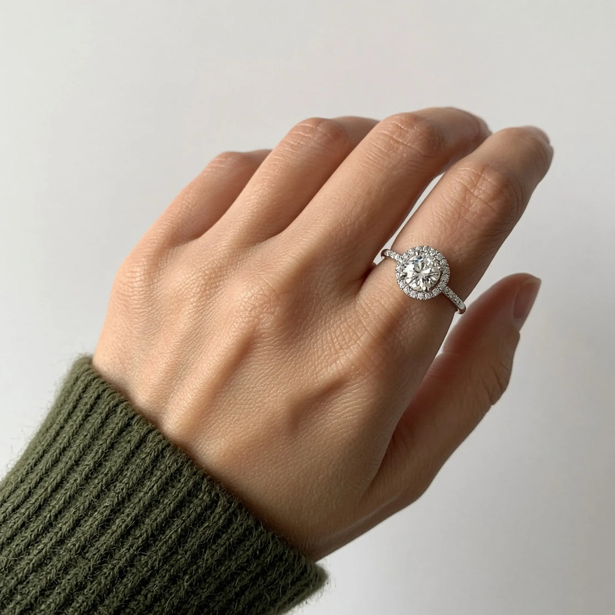 Round lab-grown diamond halo ring on the left ring finger