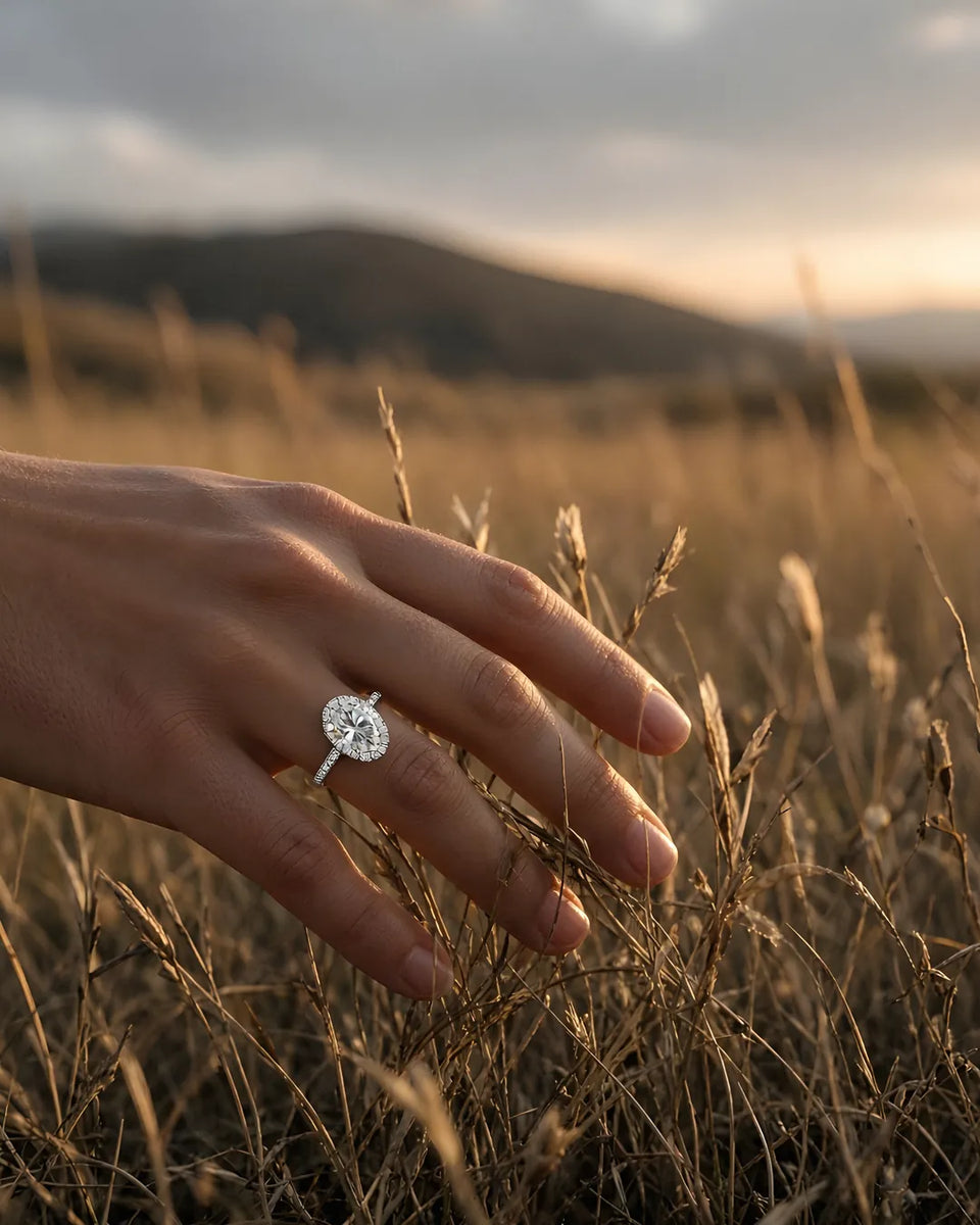 Oval halo engagement ring on the left hand at golden hour