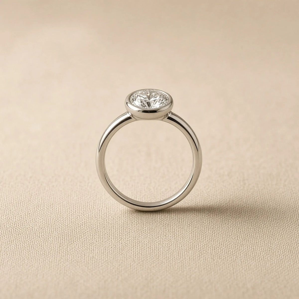 Bezel-set engagement ring in 18K white gold, side profile showing the low metal collar