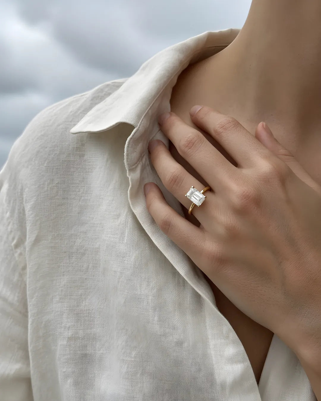 Yellow gold emerald-cut solitaire engagement ring on the left hand